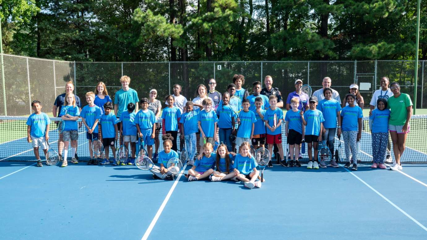 Youth tennis players standing in front of net