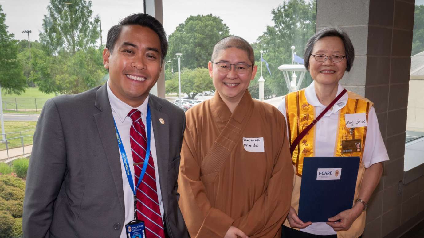 Three people smiling in front of office building window