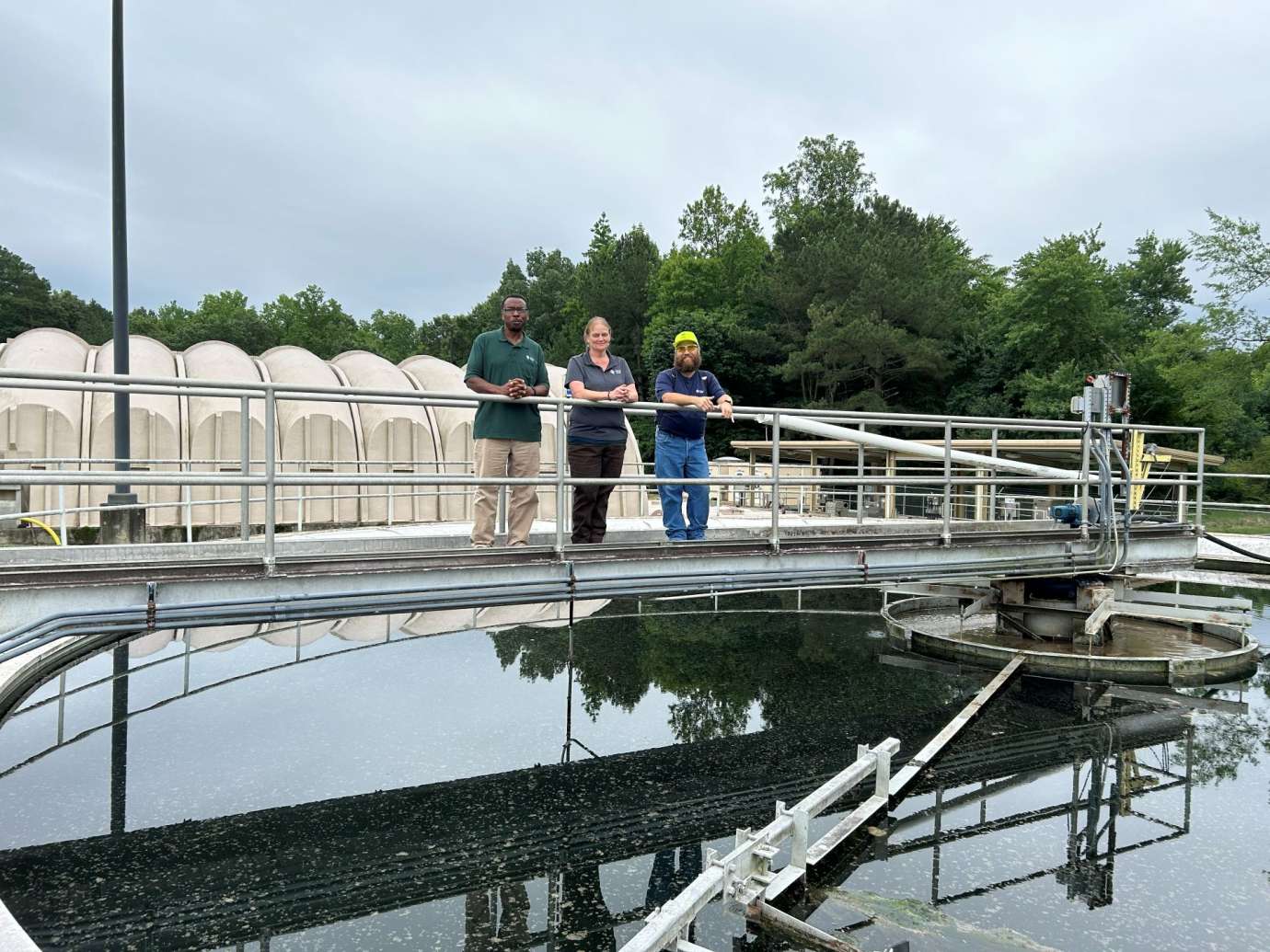 three workers stand above wastewater clarifier