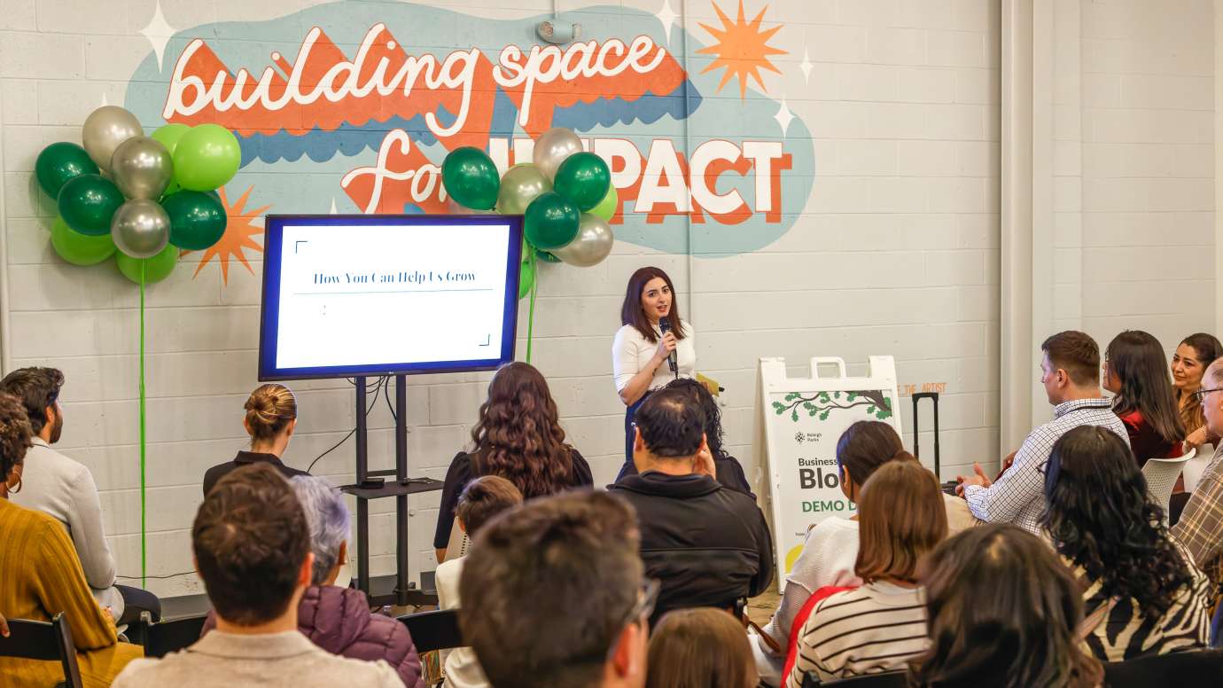 A presenter standing in front of a screen and talking to a group of people