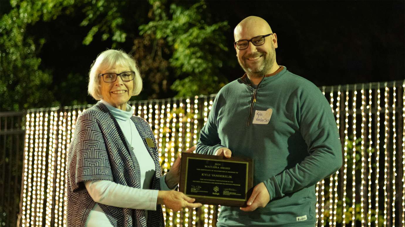 two people holding an award plaque while smiling