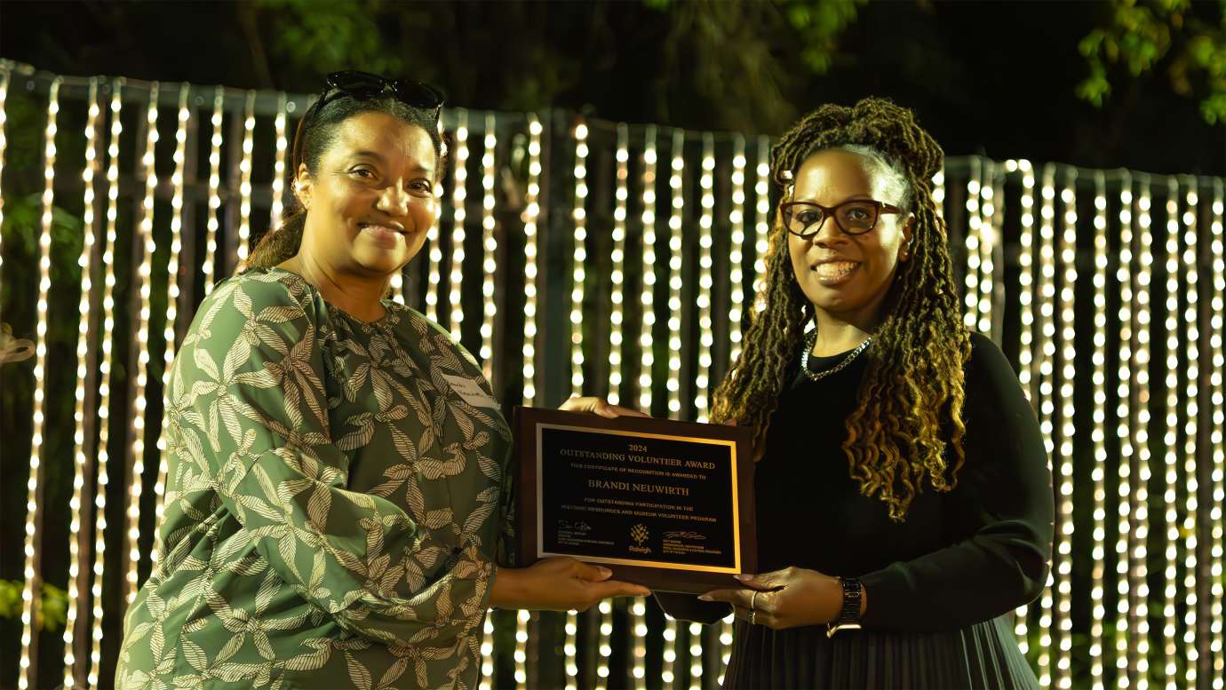 two people holding an award plaque while smiling