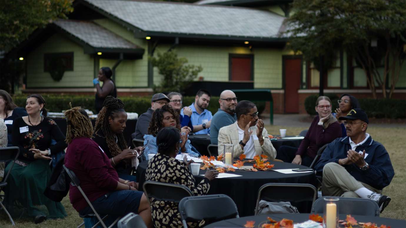 a group of people sitting at tables at pullen park