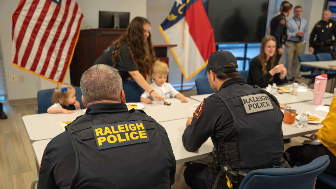 Police officers sitting at table with children
