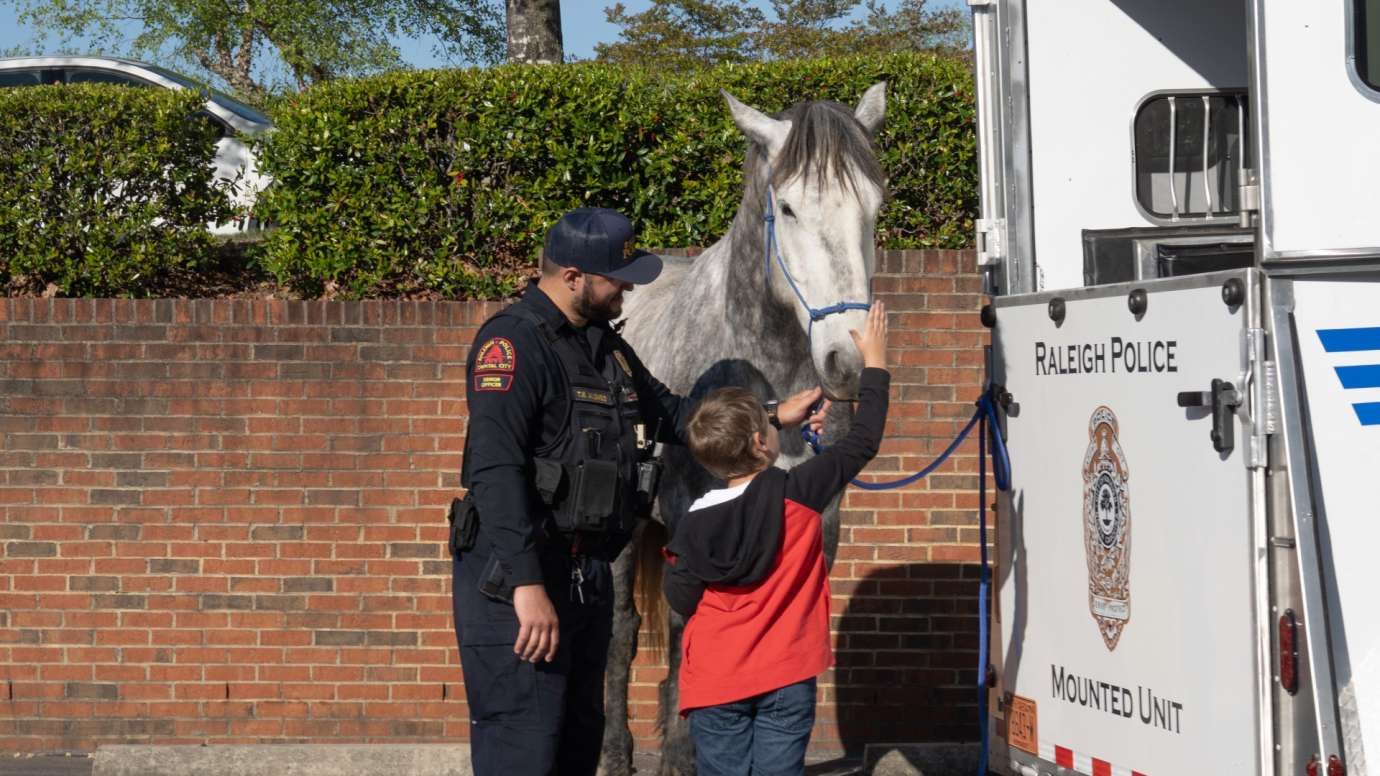 Police officer introducing child to horse