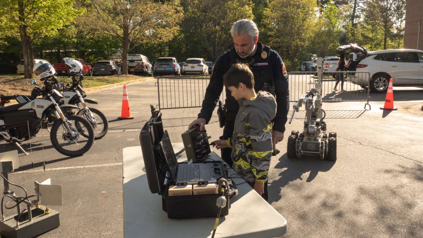 Police officer showing child laptop computer