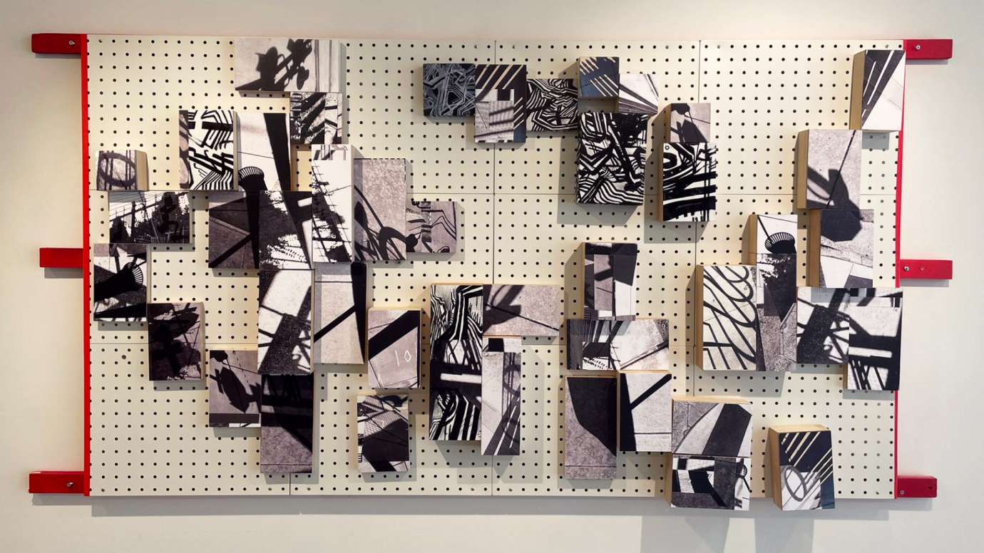 mixed media work composed of wood and a peg board in shades of black and white with red accents by Jason Lord