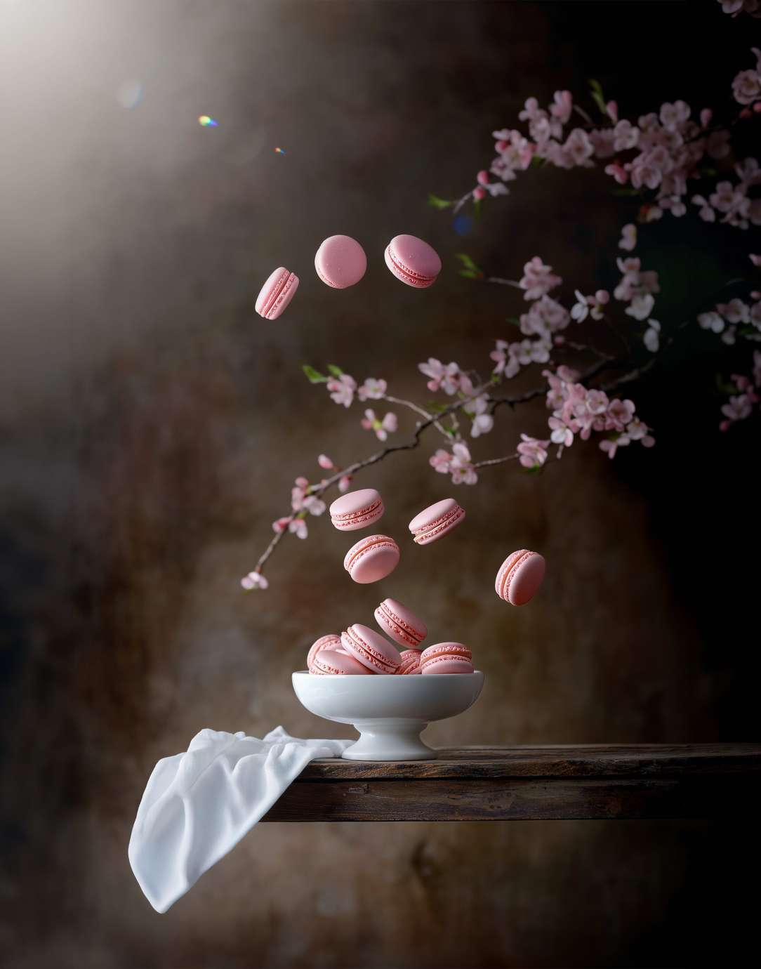 Pink macaroons floating above white bowl