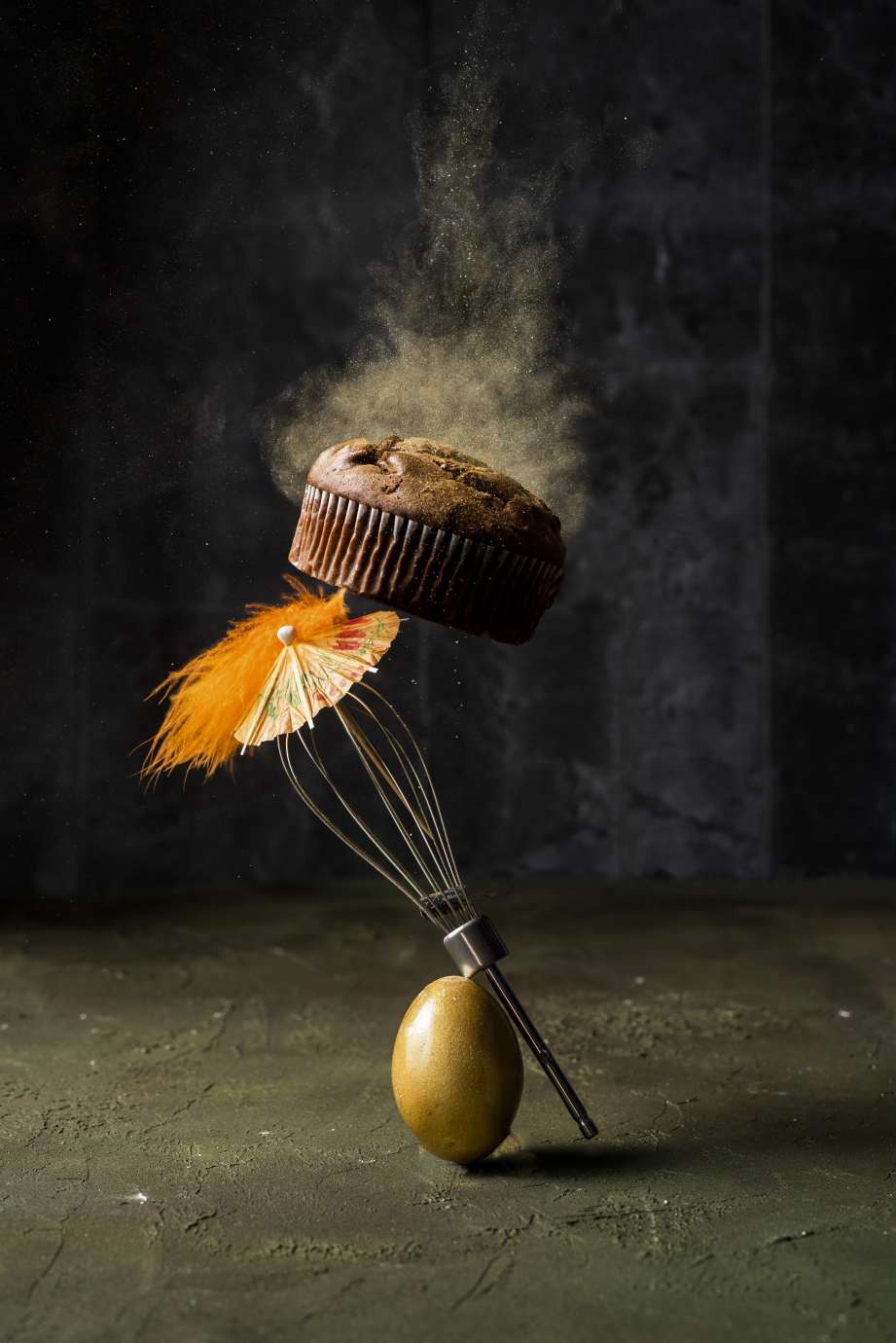 Egg, whisk, and cupcake balanced on top of each other