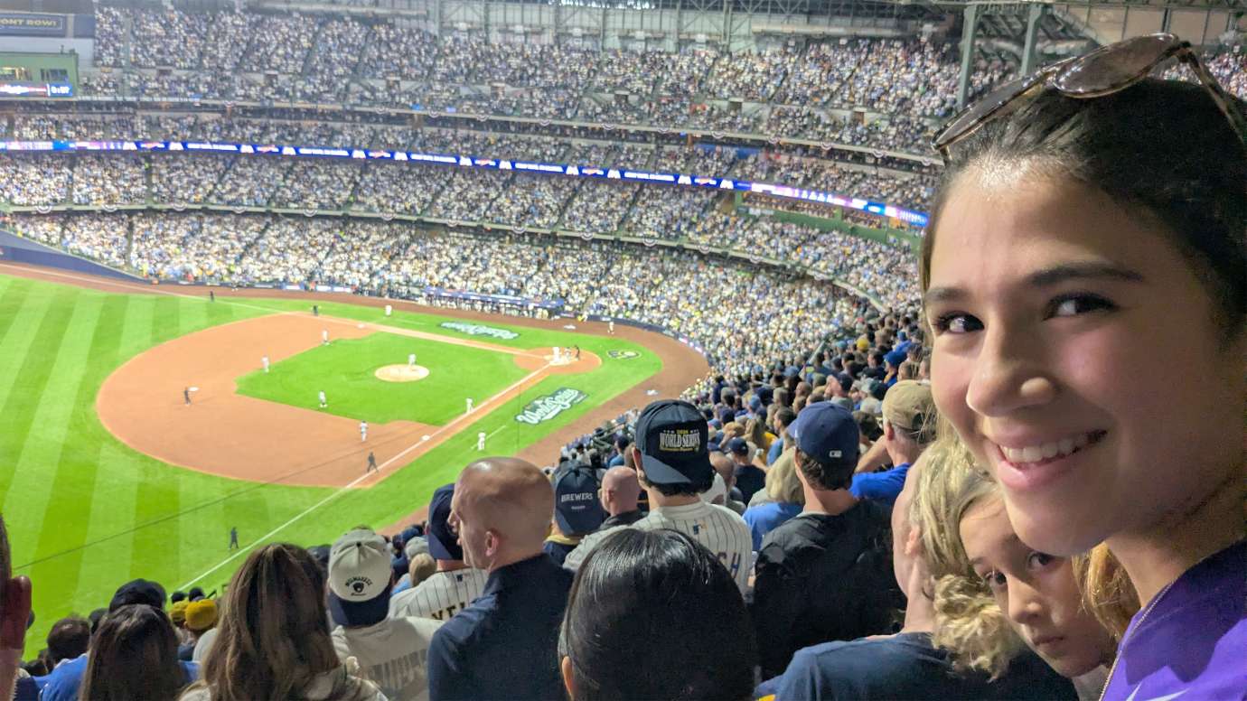a young person in the stands of a baseball game in large stadium