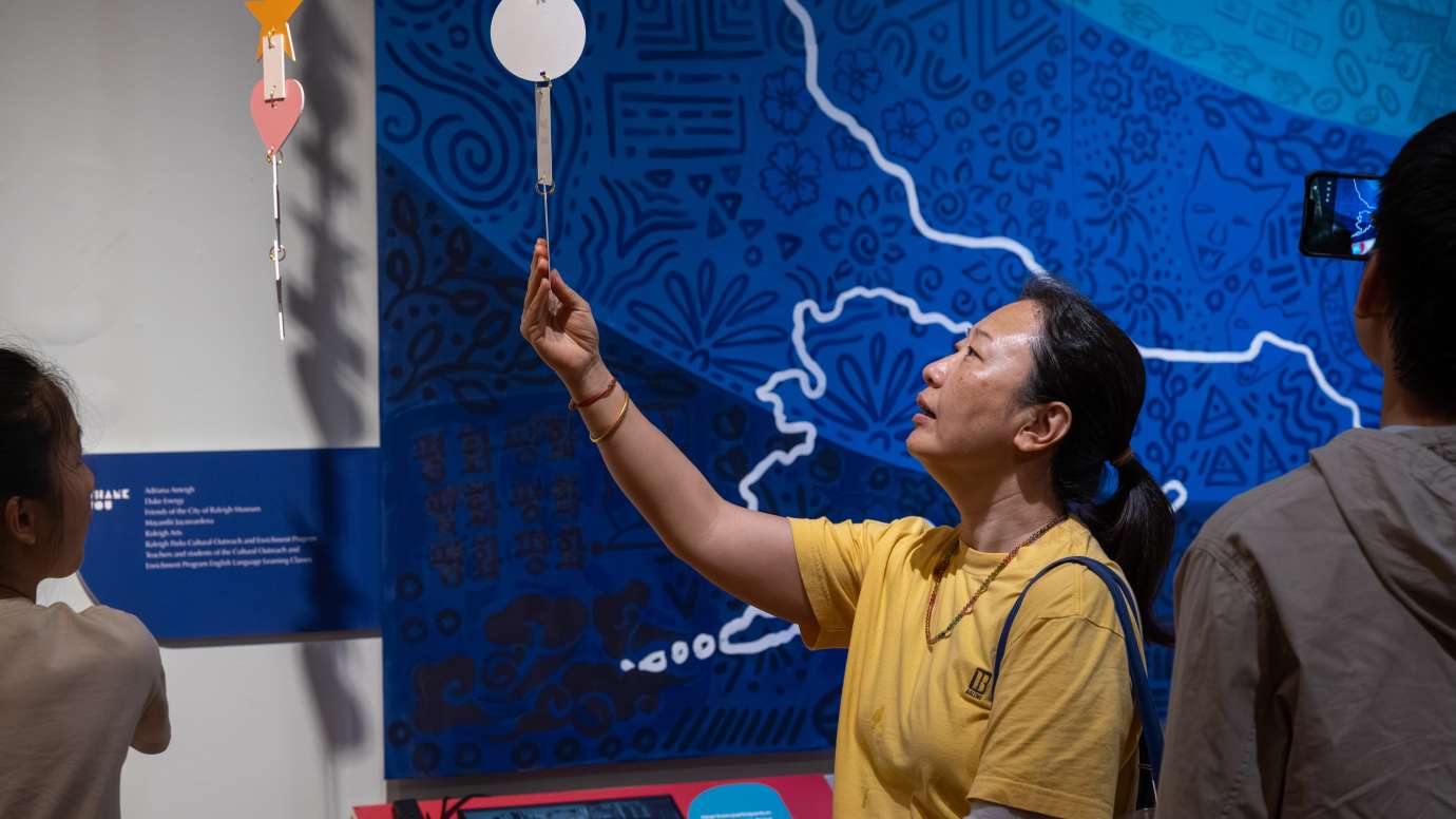 people enjoying an exhibit in front of a blue quilt