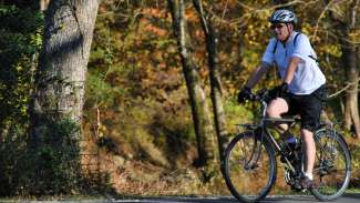 Man wearing a helmet on his bike on a Raleigh greenway. 