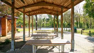 Wooden picnic shelter with view of basketball courts in the background at Apollo Heights Park