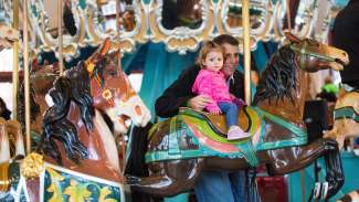 Toddler girl riding a pony on the carousel at Pullen Park