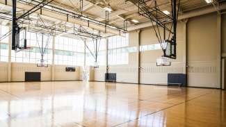 Indoor gymnasium at Abbotts Creek Park with several basketball courts and hoops. 