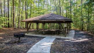 Outdoor picnic shelter at Cedar Hills Park featuring six tables and a grill 