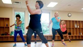 Woman smiling leading a cardio fitness class for women at Millbrook Community Center. 