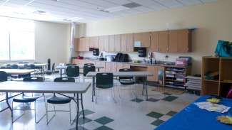 A medium size classroom with tables, chairs, a white board and two sinks at Marsh Creek 