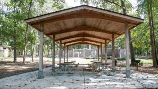 Outdoor picnic shelter with several tables and a grill at Oakwood Park 