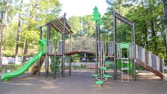 A large outdoor playground with climbing rocks, a slide, swings and more. 