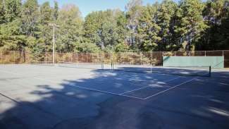 Three outdoor tennis courts with nets at Sanderford Road Park 