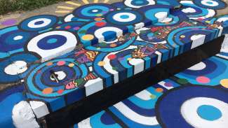 A storm drain mural with blue and white rain drops and colorful fish