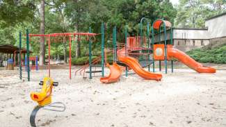 A large playground on a sand surface at Worthdale Park with slides and climbing bars.