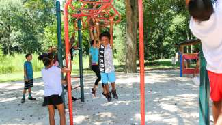 Kids enjoying the monkey bars during a summer camp at Worthdale Park