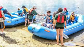 kids in two boats on shoreline as part of camp at lake wheeler