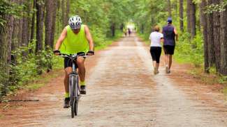 Man biking with two joggers on trail