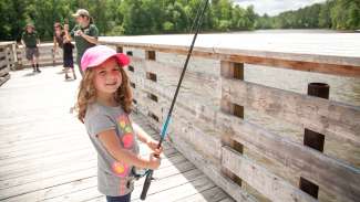 A little girl fishing off a dock 