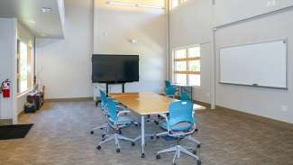 A large meeting room with a table, chairs, a white board and TV
