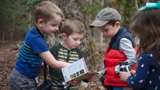 Three young kids participating in a bird watching program and learning about nature 