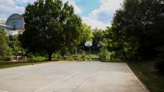 A concrete outdoor basketball court with two hoops
