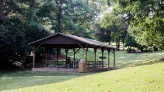 A large outdoor picnic shelter with eight tables 