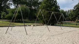 Several swings on a sand surface