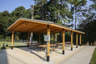 An outdoor covered picnic shelter with multiple tables 