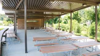 A large, open outdoor picnic shelter with over a dozen tables 