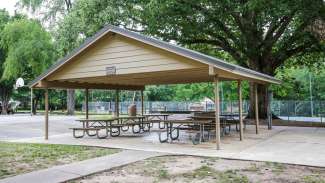 A large outdoor picnic shelter with six tables 