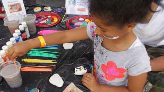A girl paints rocks at a local event