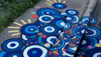 A storm drain cover painted with circles and fish by Sarah Laine Calva