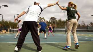 Adults participating in adult cardio on tennis courts 