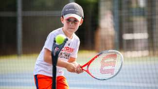 A young kid playing tennis 