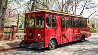 Red historic Raleigh Trolley parked at Mordecai Historic Park in spring