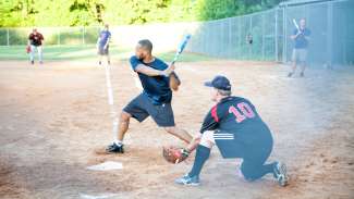 Adult softball player at home page swinging to hit ball