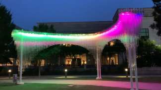 Arches over an outdoor walkway at the Duke Energy Center for the Performing Arts. Hundreds of polycarbonate tubes create an ethereal cloud-like effect during the day and an interactive luminescent sculpture in the evening.