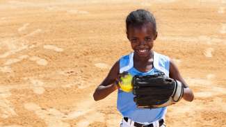 Youth girl holding softball on pitcher's mound