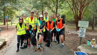 A group of park volunteers cleaning up along a greenway trail 