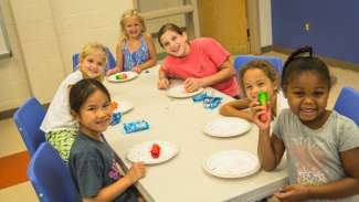 Kids sitting around table smiling doing activity