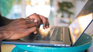 mans hands typing on a laptop